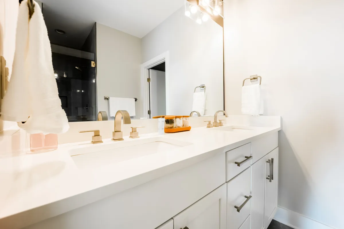 A fresh and inviting bathroom with a double sink, vanity mirror, and towel rack, creating a sense of modern comfort and practicality for daily routines.
