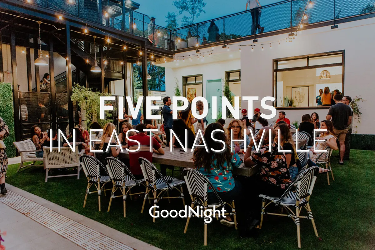 An exterior space featuring a large gathering table, string lights, abundant greenery, and modern architecture. The mood is energetic, with the setting ideal for socializing, dining, and networking—perfect for unwinding after work.